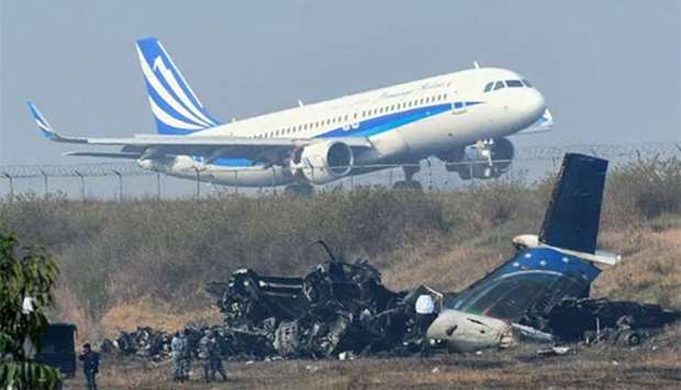 An airplane takes off at the Kathmandu international airport on Tuesday, near the wreckage of a US-Bangla Airlines plane that crashed the previous day.