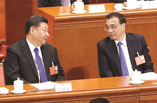 Chinese President Xi Jinping (left) talks with Premier Li Keqiang at the fourth plenary session of the National Peopleu2019s Congress at the Great Hall of the People in Beijing yesterday. China is merging its banking and insurance regulators, giving new powers to policymaking bodies such as the central bank and creating new ministries in the biggest government shake-up in years.