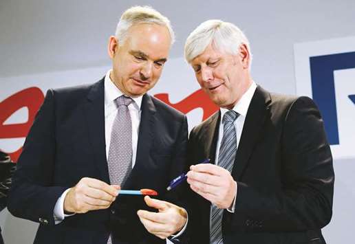 Johannes Teyssen, chief executive officer of EON (left) and Rolf Martin Schmitz, chief executive officer of RWE, exchange pens with their respective company logos following a news conference after unveiling plans for an asset swap deal between the two German utilities in Essen, Germany yesterday.