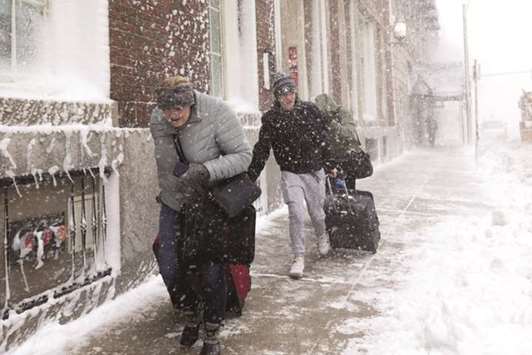 People pull luggage down Stuart Street against high winds and blowing snow as winter storm Skylar bears down in Boston, Massachusetts.