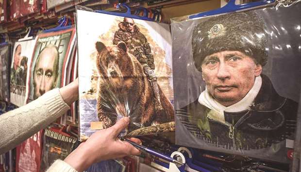 An employee presents T-shirts with images of Putin at a gift shop in Moscow. Seven candidates are lined up against him in the March 18 presidential election, but he is all but guaranteed to win, extending his Kremlin term to 2024 with a fourth term in office.