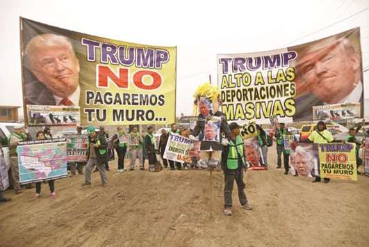 People hold signs reading u201cTrump, we will not pay for the wallu201d and u201cTrump, stop the mass deportationsu201d near the border fence between Mexico and the US, in Tijuana, Mexico, yesterday.