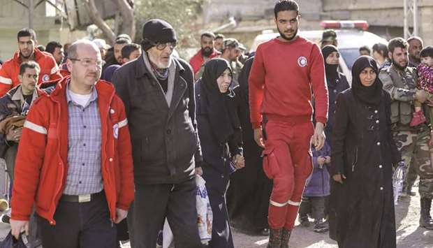 Members of the Syrian Red Crescent escort evacuated civilians from the rebel-held Eastern Ghouta enclave into the government side of the Wafideen checkpoint on the outskirts of Damascus, yesterday.