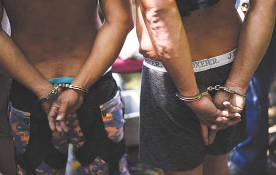 Two alleged drug dealers are handcuffed during a police operation conducted in Manila on March 15, 2018. Philippine President Rodrigo Duterte announced on Wednesday a move towards quitting the International Criminal Court, which has launched a preliminary examination of his deadly drug war.