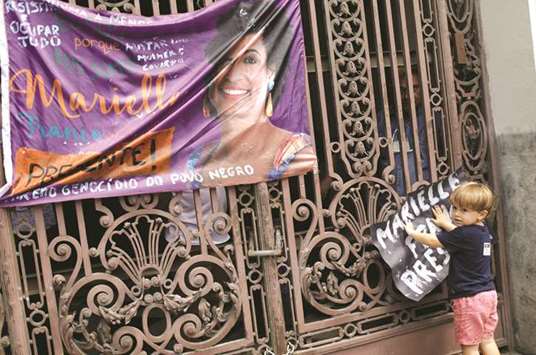 A child holds up a placard next to a banner showing slain city councillor Marielle Franco, 38, during a demonstration ahead of her wake outside the city council chamber in Rio de Janeiro.