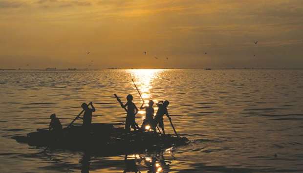 Young boys paddle in a raft in North Bay in Navotas, Metro Manila, yesterday.