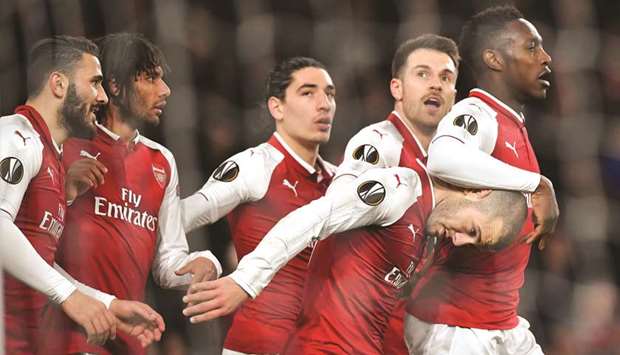 Arsenalu2019s English striker Danny Welbeck (right) celebrates with teammates scoring the teamu2019s third goal during the UEFA Europa League round of 16 second-leg match  against AC Milan at the Emirates Stadium in London on Thursday. (AFP)