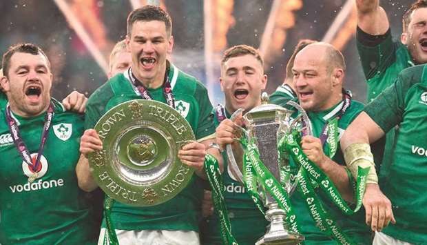 Irelandu2019s hooker Rory Best (second right) holds the Six Nations trophy and Irelandu2019s fly-half Jonathan Sexton (left) the Triple Crown as Ireland players celebrate their Six Nations Grand Slam victory after their match against England at the Twickenham, west London. (AFP)