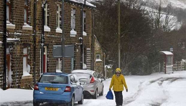 A woman walks through the snow in the village of Marsden, east of Manchester in northern England on Sunday, as the wintry weather returns to the country.
