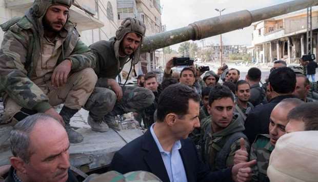 Syrian President Bashar al-Assad (C) talking with regime forces in Eastern Ghouta, in the leader's first trip to the former rebel enclave outside Damascus in years.