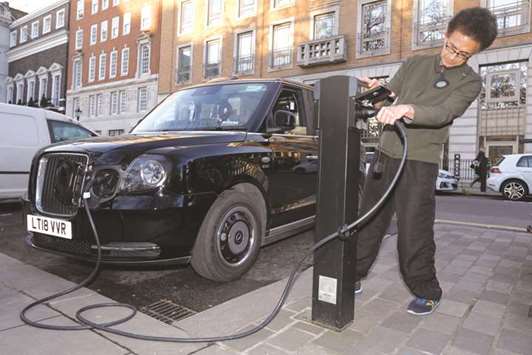 A London cab driver charges a TX City London taxi, built by the London Electric Vehicle Company, in London. The taxi is projected to travel more than 70 miles on a charge. A public charger in 45 minutes can add 50 miles of range, according to the manufacturer.
