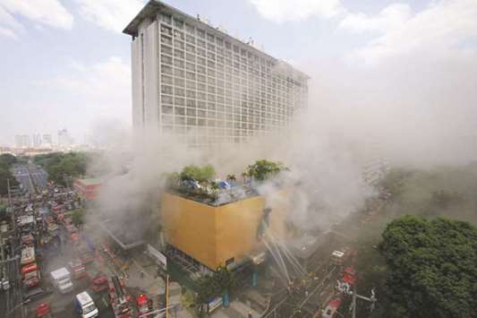 Firefighters douse water after a fire engulfed the Manila Pavilion hotel in Metro Manila, yesterday.
