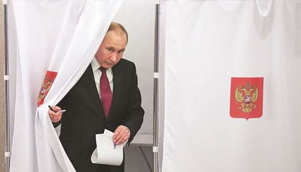 President Vladimir Putin walks out of a voting booth at a polling station in Moscow yesterday.