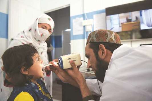 A paramedic checks a childu2019s throat at a telemedicine online treatment centre run by the government of Khyber Pakhtukhwa in the remote Behali area in Mansehra district.