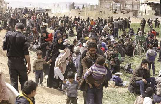 Syrian civilians evacuated from the eastern Ghouta enclave rest as they pass through the regime-controlled corridor opened by the government forces in Hawsh al-Ashaari, east of the enclave town of Hammuriyeh (Hamouria) on the outskirts of the capital Damascus, yesterday.
