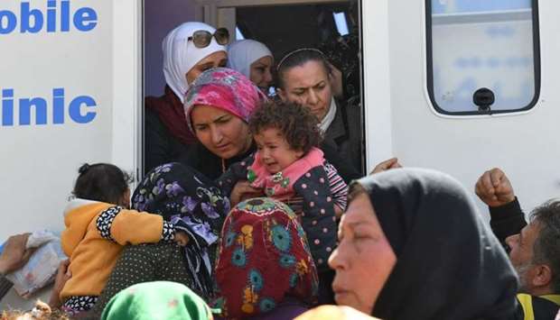 Civilians, fleeing the city of Afrin in northern Syria, gather around a World Health Organization (WHO) field clinic in the village of az-Ziyarah, in the government-controlled part of the northern Aleppo province.
