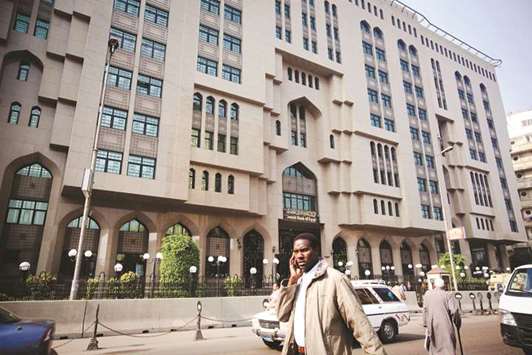 A pedestrian uses his mobile phone as he passes the Central Bank of Egypt in Cairo (file). The short-term treasury yields have declined since the middle of last year on the back of lower inflation, which prompted the central bank to cut rates last month for the first time since the float, by 100 basis points.