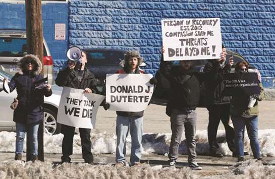 Demonstrators, including one with a sign comparing President Trump to Philippines President Duterte, protest across the street as US President Donald Trump visits a firehouse during a visit to New Hampshire devoted to the subject of u201ccombatting the opioid crisisu201d in Manchester, New Hampshire, US.