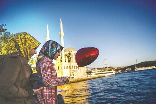 A woman holds a balloon as she goes about with her daily life near the Bosphorus bridge at the Ortakoy district in Istanbul (file). Turkey was the biggest consumer of Muslim consumer clothing with a market of $25.7bn in 2015, according to the latest data on the State of the Global Islamic Economy report.