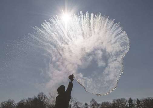 A woman tosses hot water into the freezing cold air yesterday and watches it turn into a sparkling cloud of snow.
