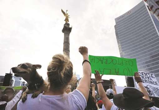 People affected by the September 19, 2017 earthquake take part in a march yesterday to mark the six-month anniversary of the quake in Mexico City. In the background, the Angel of Independence monument is seen.