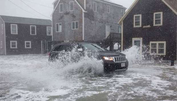 A vehicle drives through floodwaters during a coastal storm in Scituate, Massachusetts on Friday.