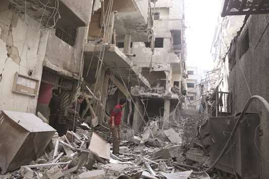 Syrians look for survivors following government shelling on the rebel-held besieged town of Ayn Tarma in the eastern Ghouta region on the outskirts of the capital Damascus, yesterday.