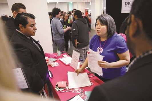 A company representative speaks with job seekers during a career fair in Los Angeles. Initial claims for state unemployment benefits increased 3,000 to a seasonally adjusted 229,000 for the week ended March 17, the Labour Department said yesterday.