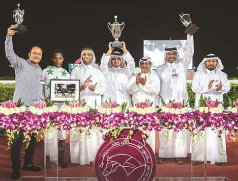 Qatar Racing and Equestrian Club deputy chief steward Abdulla Rashid al-Kubaisi (third from right) and Saad al-Hajri (right), head of Grandstand and Protocol, with the winners of the Mesaimeer Cup after Sheikh Faisal bin Hamad bin Jassim al-Thaniu2019s Topsy Turvy won the 1800m dirt feature at the QREC. PICTURES: Juhaim