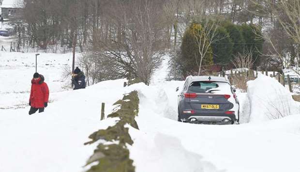 A couple check on their car left stranded on a snow blocked road between Delph and Denshaw in northern England yesterday.