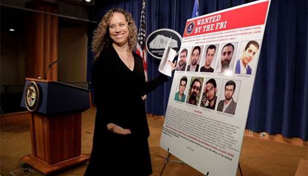 A staff member reacts as she posts pictures of nine Iranians charged with conducting massive cyber theft campaign before Deputy Attorney General Rod Rosenstein's news conference at the Justice Department in Washington on Friday.