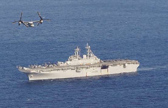 USS Wasp amphibious assault carrier sails as a US Marine Corps MV-22 Osprey aircraft flies near the ship during their operation in the waters off Okinawa, yesterday.