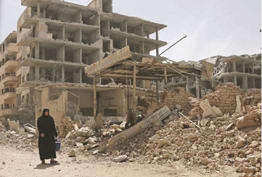 A Syrian woman walks past damaged buildings after a ceasefire came into effect in Zamalka, one of the few remaining rebel-held pockets in Eastern Ghouta, on the outskirts of Damascus, yesterday.