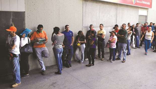 People stand in a queue to get into a Banco de Venezuela branch to withdraw cash in Caracas, Venezuela, yesterday.