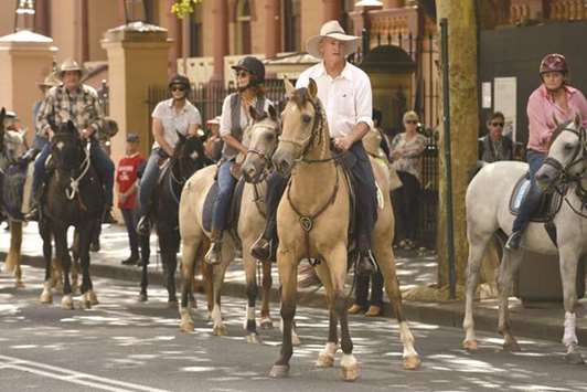 Protesters on horseback ride past an environmental rally in Sydney.
