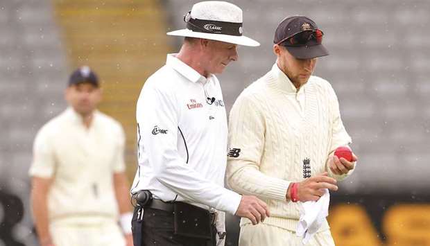 Englandu2019s captain Joe Root (left) inspects the ball with umpire Paul Reiffel as they walk off the field during a rain delay on the third day of the first Test in Auckland yesterday. (Reuters)
