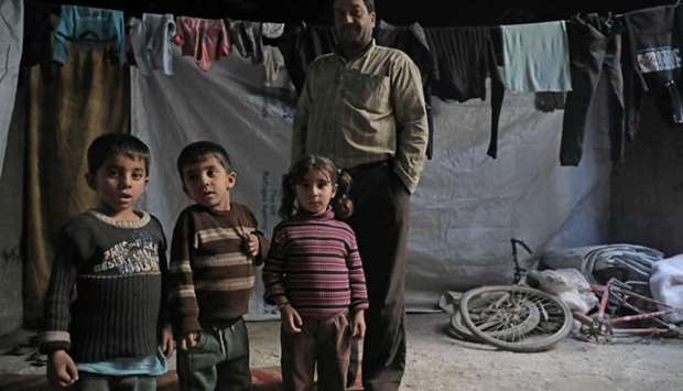A Syrian man and children stand in a basement used as a shelter against air strikes, in Douma, in Eastern Ghouta on the outskirts of the capital Damascus.