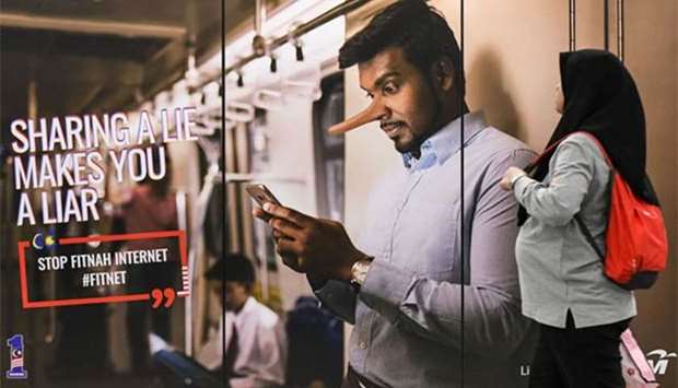 A commuter walks past an advertisement reading ,sharing a lie makes u a liar, at a train station in downtown Kuala Lumpur on Monday. The Malaysian government has tabled a bill in parliament to combat ,fake news,.