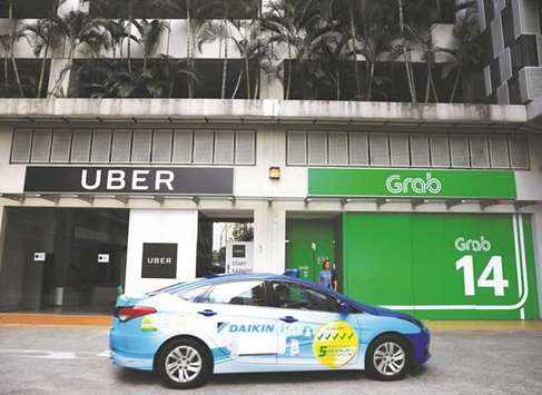 A ComfortDelgro taxi passes Uber and Grab offices in Singapore. Grab said the Uber acquisition accelerated its path to profitability in its core transport business, as it would become the most  cost-efficient Southeast Asian platform.