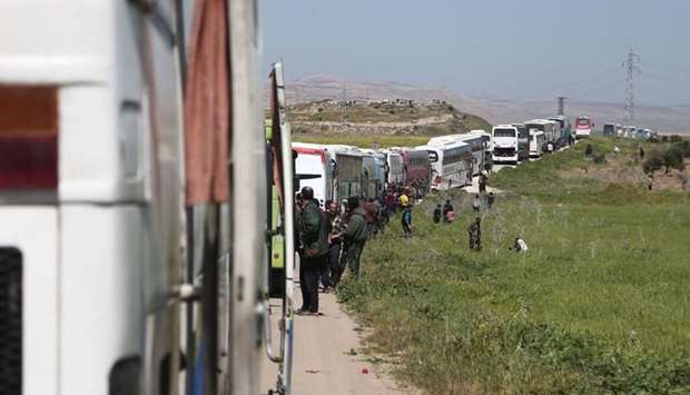 A convoy transporting Syrian civilians and rebel fighters evacuated from Eastern Ghouta waits in a government-held area prior to entering the village of Qalaat al-Madiq, some 45 kilometres northwest of the central city of Hama.