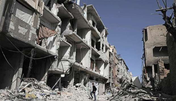 A Syrian man walks down a street past destoyed buildings in Douma, in Eastern Ghouta