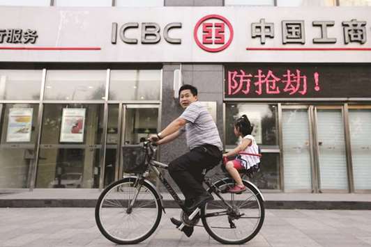 A man and his daughter ride a bicycle past a branch of the Industrial and  Commercial Bank of China in Beijing. ICBC reported a non-performing loan ratio of 1.55%, versus 1.62% a year ago.