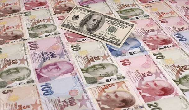 A file photo illustration taken on January 7, 2014 in Istanbul shows a 100 US dollar banknote against Turkish lira notes of various denominations. The lira has fallen 5% against the dollar so far this year.