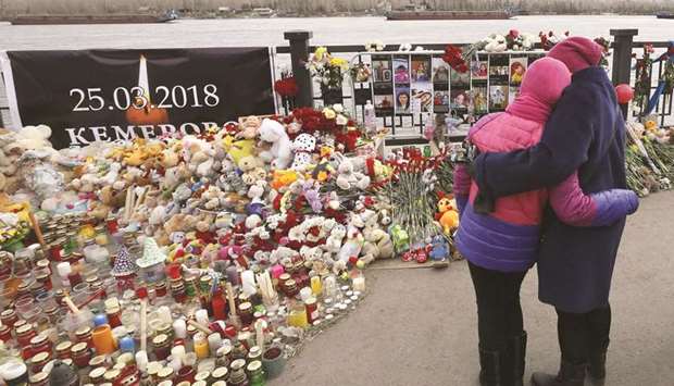 Mourners stand in front of a makeshift memorial on the day of national mourning for the victims of a shopping mall fire in Kemerovo on an embankment of the Yenisei River in the Siberian city of Krasnoyarsk.