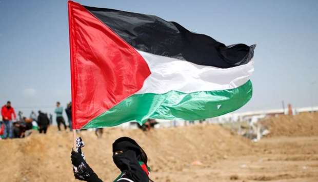 A woman waves a Palestinian flag along Israel border with Gaza