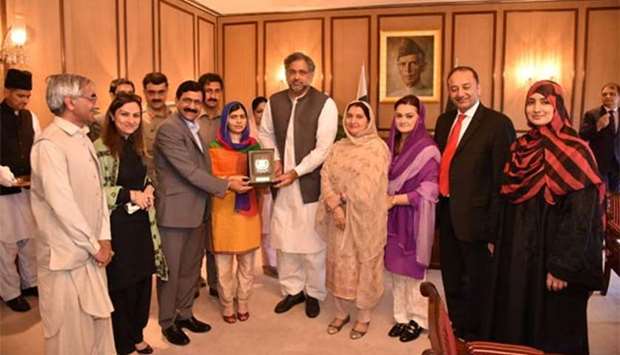 Nobel Peace Prize laureate Malala Yousafzai (wearing orange dress) receives a shield from the Pakistan Prime Minister Shahid Khaqan Abbasi in Islamabad on Thursday.