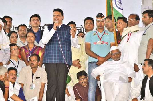 Maharashtra Chief Minister Devendra Fadnavis speaks at Ramlila Maidan in New Delhi yesterday as social activist Anna Hazare looks on.