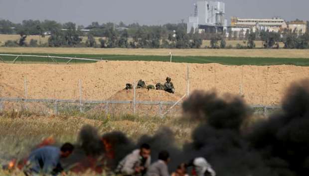 Palestinians take cover from Israeli snipers during clashes at the Gaza-Israel border at a protest demanding the right to return to their homeland, in the southern Gaza Strip.