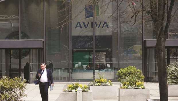A pedestrian uses a mobile handset as he passes the headquarters of Aviva in London (file). At the height of concerns over a potential trade war, Aviva eliminated some of its short dollar positions, made bearish bets on South Korean assets versus the Japanese yen and moved from overweight to neutral on local-currency bonds.