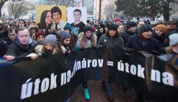 People hold portraits of murdered Slovak journalist Jan Kuciak and his girlfriend Martina Kusnirova and a banner reading ,Attacking a journalist = attacking all of us, during a silent protest march